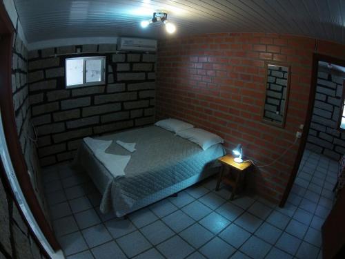 a small bedroom with a bed in a brick wall at Pousada Louise in Pinheira