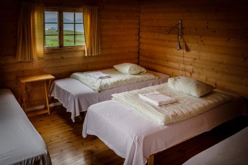 a room with two beds in a log cabin at Ósar Hostel in Tjörn
