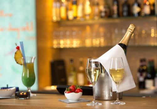a bottle of wine sitting on a table with two glasses at BRUGGER'S Hotelpark am See in Titisee-Neustadt