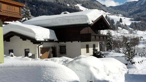a house covered in snow next to a mountain at Ferienhaus Gschwandtl in Kleinarl
