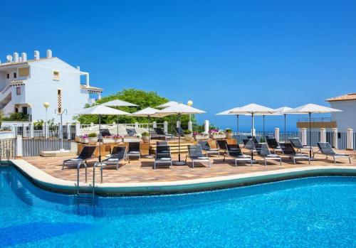 a swimming pool with chairs and umbrellas and a table and chairs at Sea View Penthouse Apartment Monte Pego in Pego