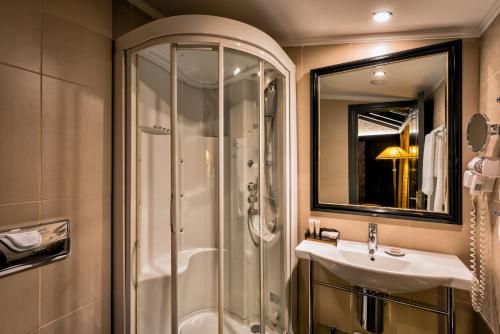 a bathroom with a shower and a sink and a mirror at Maison Grecque Hotel Extraordinaire in Patra