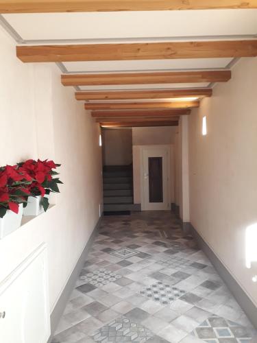 a hallway with wood ceilings and red flowers in a vase at Aosta Romana case vacanza in Aosta