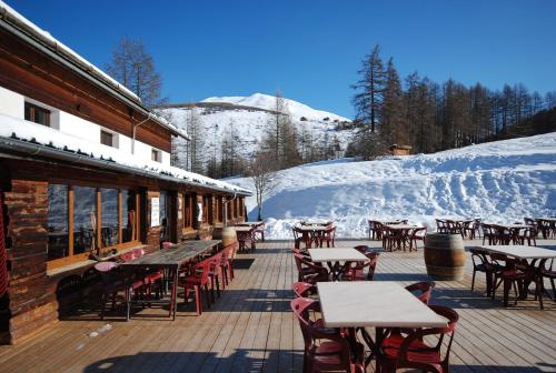a patio with tables and chairs in the snow at Hotel Spa L'Equipe in Molines-en-Queyras