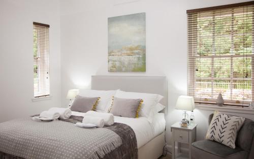 a white bedroom with a bed and a chair at The Gardener's Cottage in Dunblane