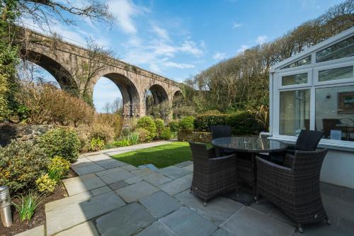 a patio with a table and chairs in front of a bridge at Carbis Bay and Spa Hotel in St Ives