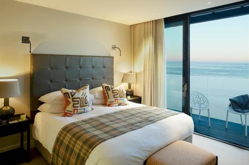 a bedroom with a large bed and a large window at Carbis Bay and Spa Hotel in St Ives