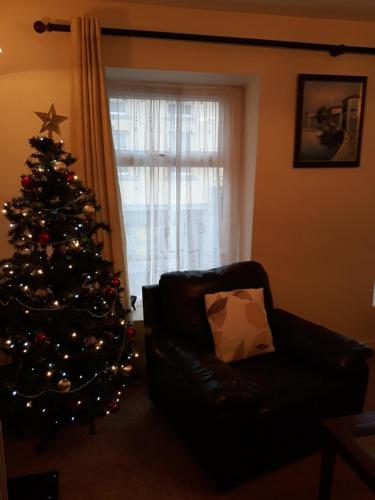 a christmas tree in a living room with a couch at Swinford Bridge Street Apartment in Swinford