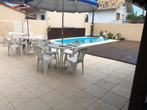 una mesa con sillas y una sombrilla junto a la piscina en Casa Ingleses, en Florianópolis