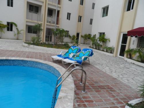 a resort with a swimming pool and two chairs next to a building at Apartamento Aquarel in Boca Chica