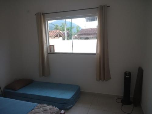 a room with a window with a bed and a windowseat at Casa de praia litoral norte SP in Caraguatatuba