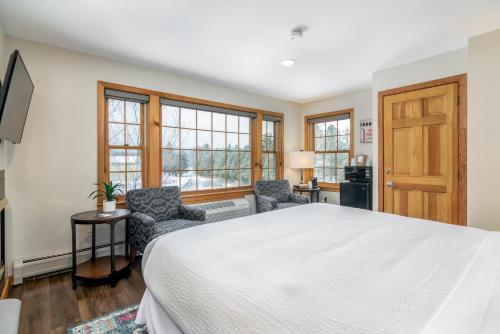 a bedroom with a large bed and two chairs at Grey Fox Inn in Stowe