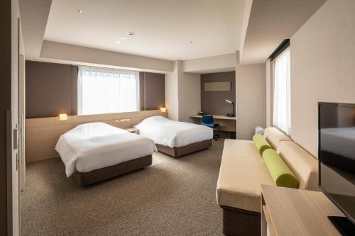 a hotel room with two beds and a flat screen tv at JR Clement Inn Takamatsu in Takamatsu