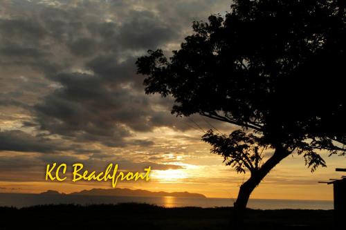 a sunset with a tree and the words kc breakfast at KC Beachfront in Marang