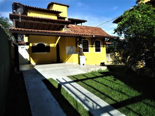 a yellow house with a grass yard in front of it at Vila do Sossego in Cabo Frio