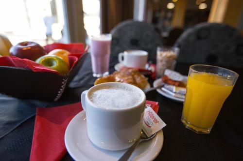 a table with a cup of coffee and a glass of orange juice at Hotel Sol Bariloche in San Carlos de Bariloche