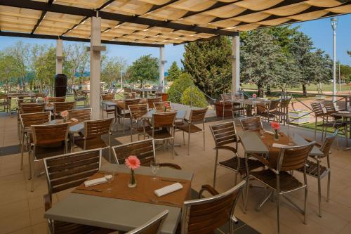 an empty restaurant with tables and chairs and trees at Camping Park Umag Mobile Homes in Umag