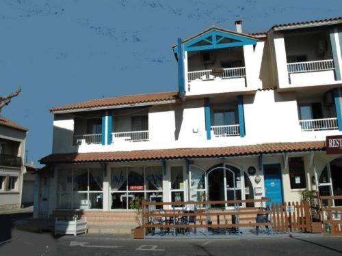 un bâtiment avec des tables et des chaises devant lui dans l'établissement Hotel Alcyon, à Valras-Plage