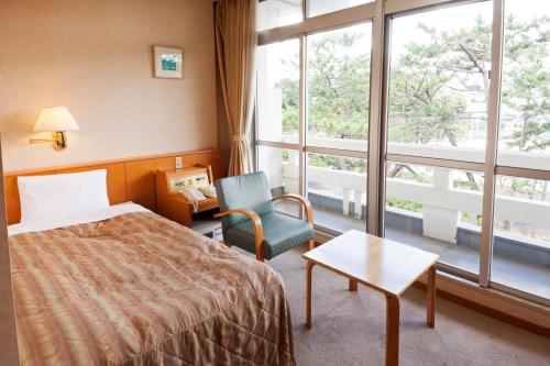 a hotel room with a bed and a chair and a window at Hotel Axia Kushikino in Ichikikushikino