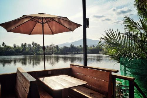 a bench with an umbrella next to a body of water at The Hideaway in Kampot