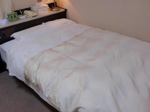 a white bed in a room with a telephone at Tsuyama Central Hotel Townhouse in Tuyama