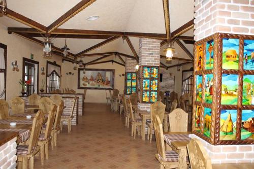 una sala da pranzo con tavoli, sedie e vetrate istoriate di HANUL TENTEA a Săcel
