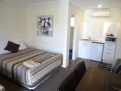 a small bedroom with a bed and a kitchen at Centrepoint Motel in Dubbo