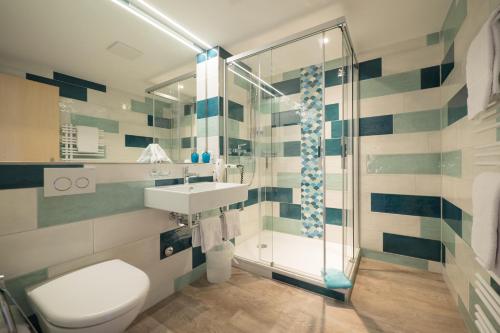een badkamer met een douche, een toilet en een wastafel bij Hotel Alpenblick Mürren in Mürren