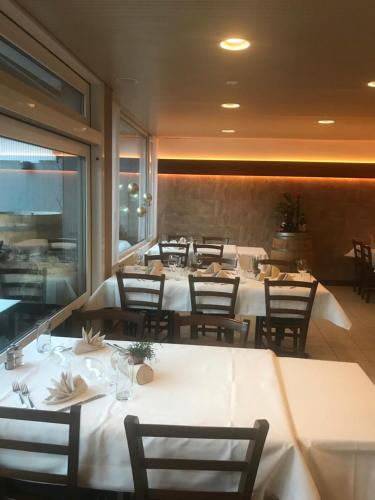 a dining room with white tables and chairs at Hotel Hahnenblick in Engelberg