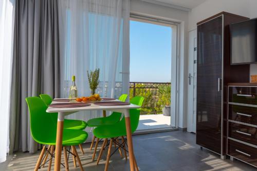 a dining room with a table and green chairs at Apartmani Dalmacjia in Grebaštica