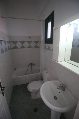 a white bathroom with a sink and a toilet at UMBRELLA BEACH APARTMENTs in Kavos