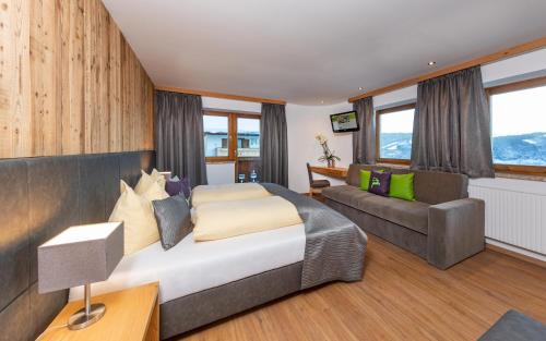 a bedroom with a bed and a couch at Das Grünholz Aparthotel in Mühlbach am Hochkönig