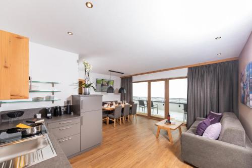 a kitchen and living room with a couch and a table at Das Grünholz Aparthotel in Mühlbach am Hochkönig