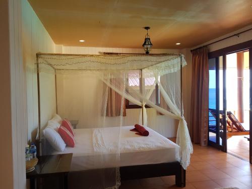 a bedroom with a canopy bed with a balcony at Aow Leuk Grand Hill in Koh Tao