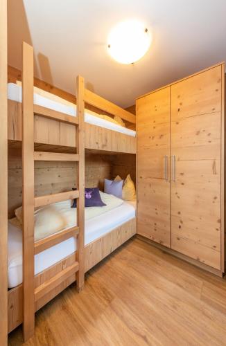 a bedroom with two bunk beds and wooden cabinets at Das Grünholz Aparthotel in Mühlbach am Hochkönig