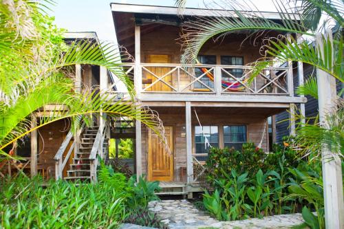 a wooden house with a balcony and palm trees at Las Rocas Resort and Dive Center in West Bay