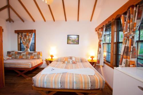 a bedroom with two beds and two windows at Las Rocas Resort and Dive Center in West Bay