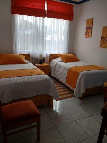 a bedroom with two beds and a window at Drake Inn in Puerto Villamil