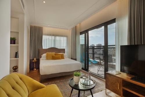 a bedroom with a bed and a television and a balcony at Hotel Jacob Samuel by Prima Hotels in Tel Aviv