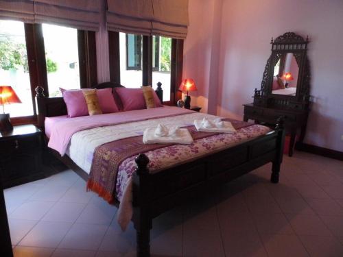 a bedroom with a bed with pink pillows and a mirror at Majestic Villas Guesthouse Phuket. in Rawai Beach