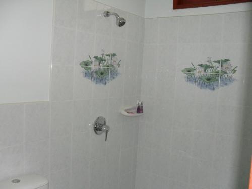 a bathroom with a shower with plants on the wall at Majestic Villas Guesthouse Phuket. in Rawai Beach