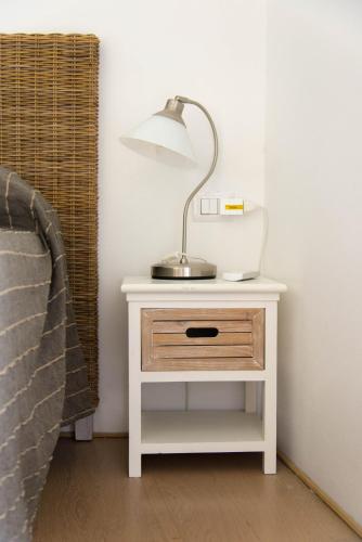 a white nightstand with a lamp on it next to a bed at Il Gamberino in Capraia