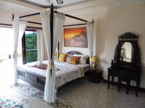 ein Schlafzimmer mit einem Himmelbett und einem Fenster in der Unterkunft Majestic Villas Guesthouse Phuket. in Rawai Beach