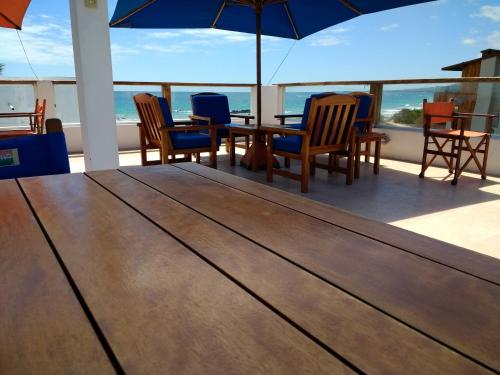 a deck with a table and chairs and an umbrella at Drake Inn in Puerto Villamil