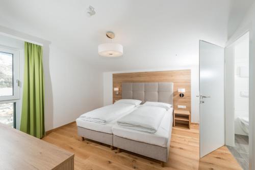 a bedroom with a white bed and a green curtain at Panorama Lodge Premium Apartments in Schladming