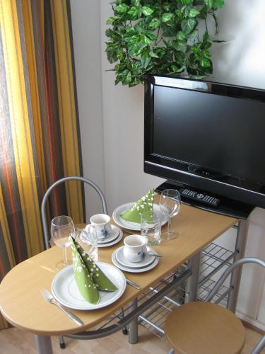 a dining room table with a television and a table with glasses at Guesthouse Golden Goose in Kittilä