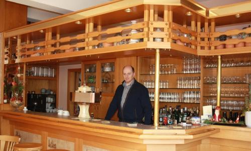 a man standing behind a counter in a bar at Hotel zur Waage in Bad Münstereifel