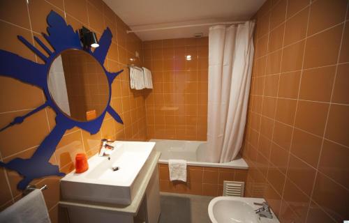 a bathroom with a sink and a mirror and a tub at Hotel Made Inn in Portimão