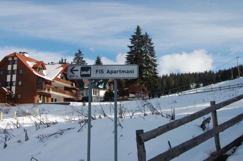 a street sign in the snow next to a fence at Lux - Apartment Snow Oasis in Vlasic