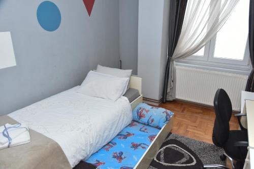 a small bedroom with a bed and a chair at Blue House Apartment in Niš